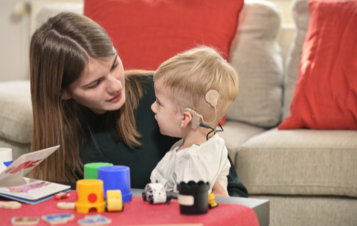 Un niño con implantes cocleares jugando con una mujer joven 